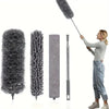 A woman is using a retractable electrostatic dust duster with a microfiber head to clean a surface.