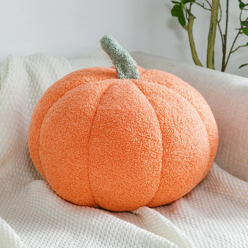 An orange, fuzzy Halloween pumpkin plush pillow resting on a white textured fabric.