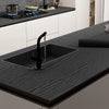 A black kitchen sink installed in a dark gray wood grain countertop with a modern faucet.