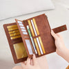 A hand holds an open brown leather RFID-blocking wallet displaying various cards and cash inside.