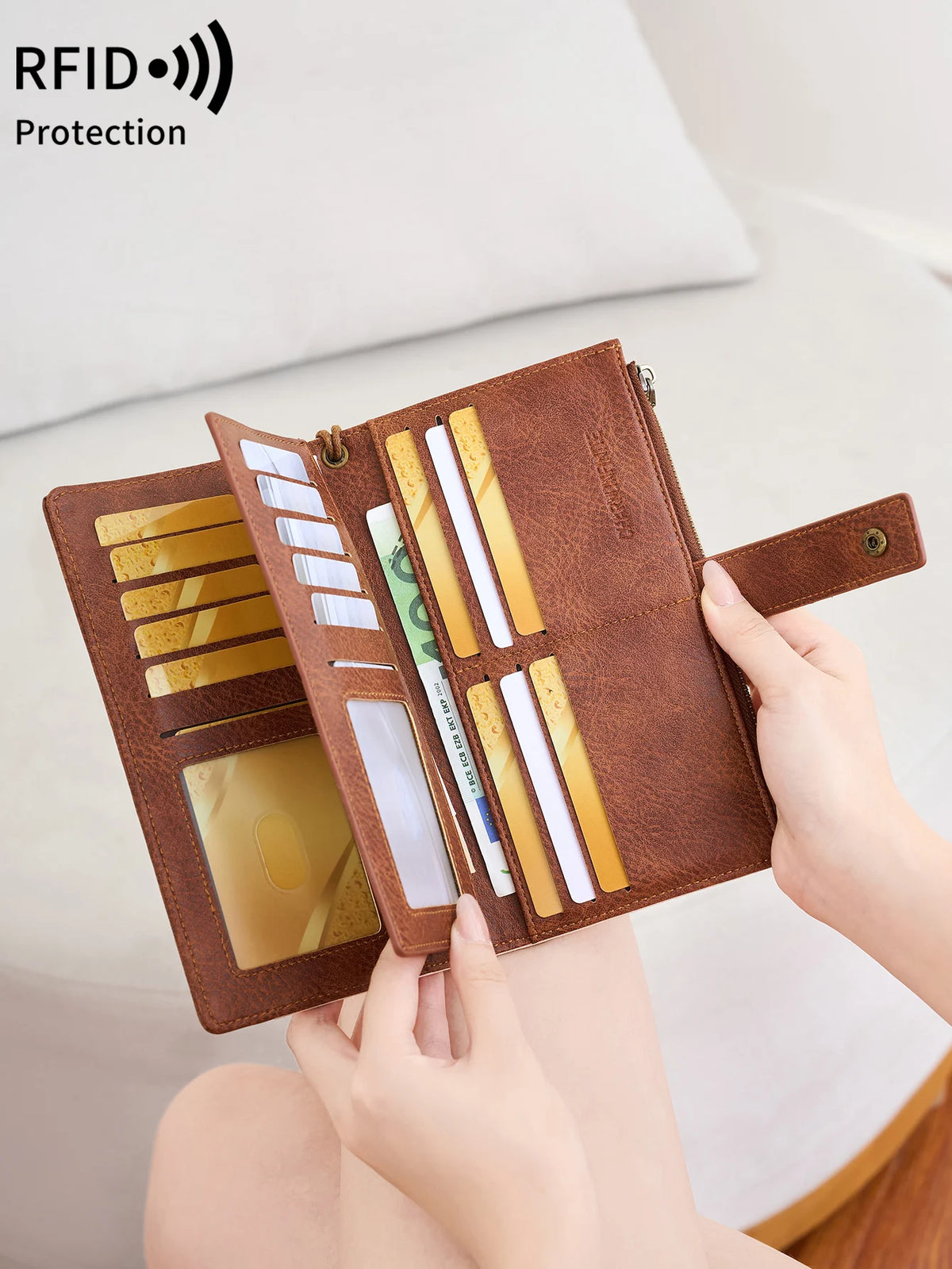 A hand holds an open brown leather RFID-blocking wallet displaying various cards and cash inside.