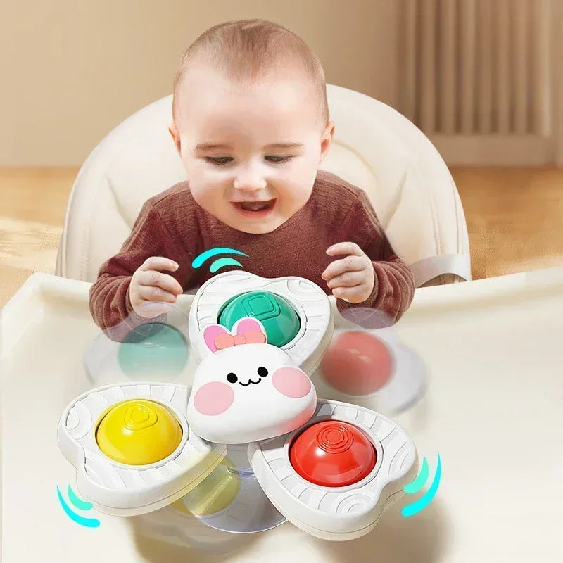 A baby is interacting with a set of spinning bath toys, including water wheels and a floating sphere.