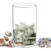 A clear acrylic piggy bank filled with coins and bills, next to various coins and a cat.