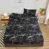 Black and white marbled print fitted bed sheet displayed on a bed with pillows and surrounding decor.
