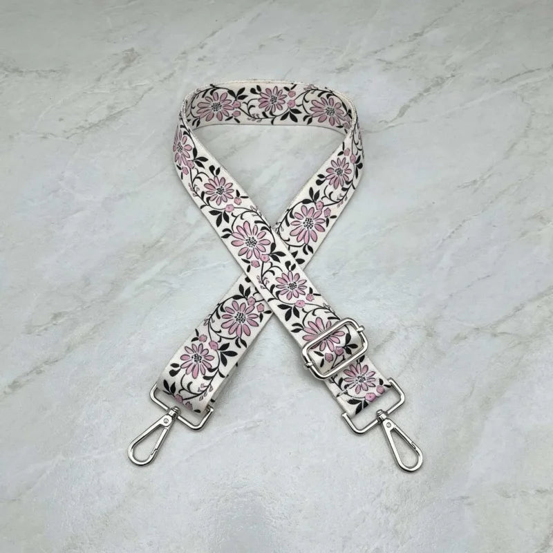 A beige and pink floral patterned fabric strap for an adjustable crossbody bag.