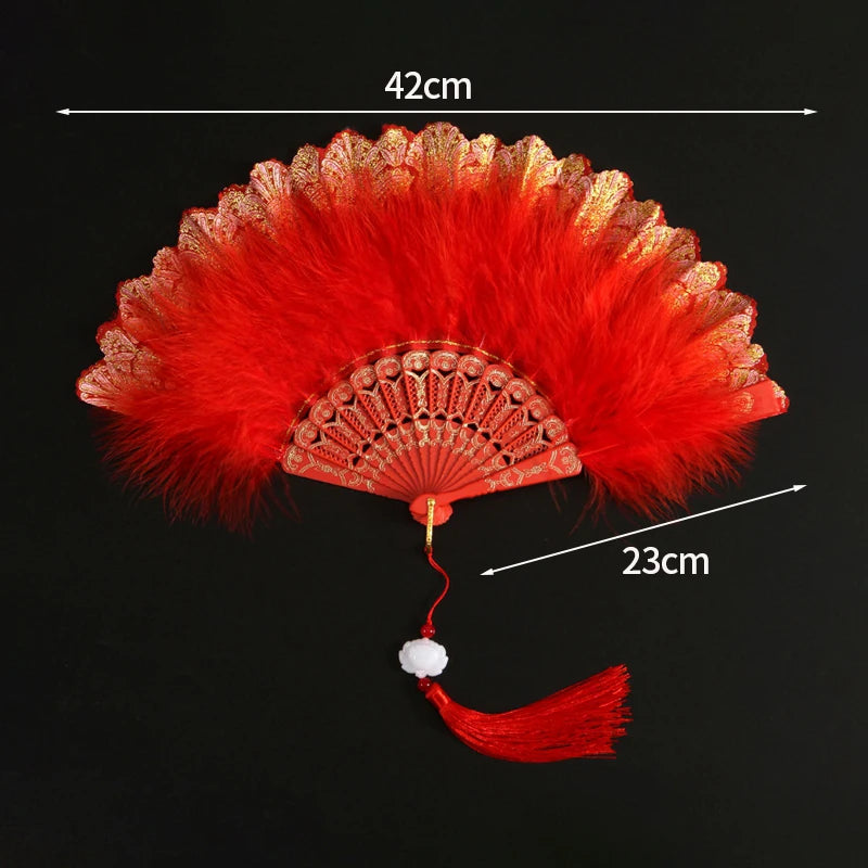 A vibrant red lace folding hand fan with a decorative fan and a tassel, shown against a black background.