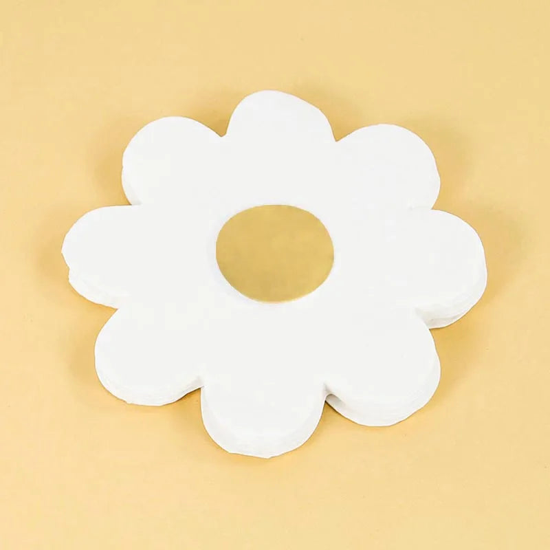 A white, flower-shaped disposable party item with a cutout center is shown on a light beige surface.