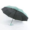 A black and mint green automatic foldable umbrella open and angled against a white background.