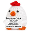 A white crochet chick doll with a red tuft on its head and a positive message card.