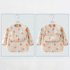 A beige long sleeve feeding bib for a child with a catch pocket, featuring an all-over pattern of carrots and fruit.