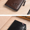 A dark brown leather wallet with a zipper closure and a silver embossed kangaroo design resting on a wooden surface.