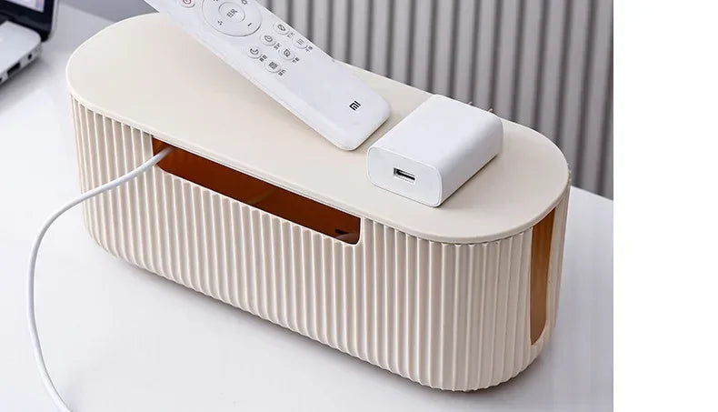 A beige cable management box with a lid and power strip organizer is shown on a white surface.