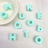 Perles en acrylique bleu clair formant les lettres HOUKE et TO