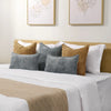 A collection of decorative cushion covers in shades of gray, beige, and white displayed on a bed.