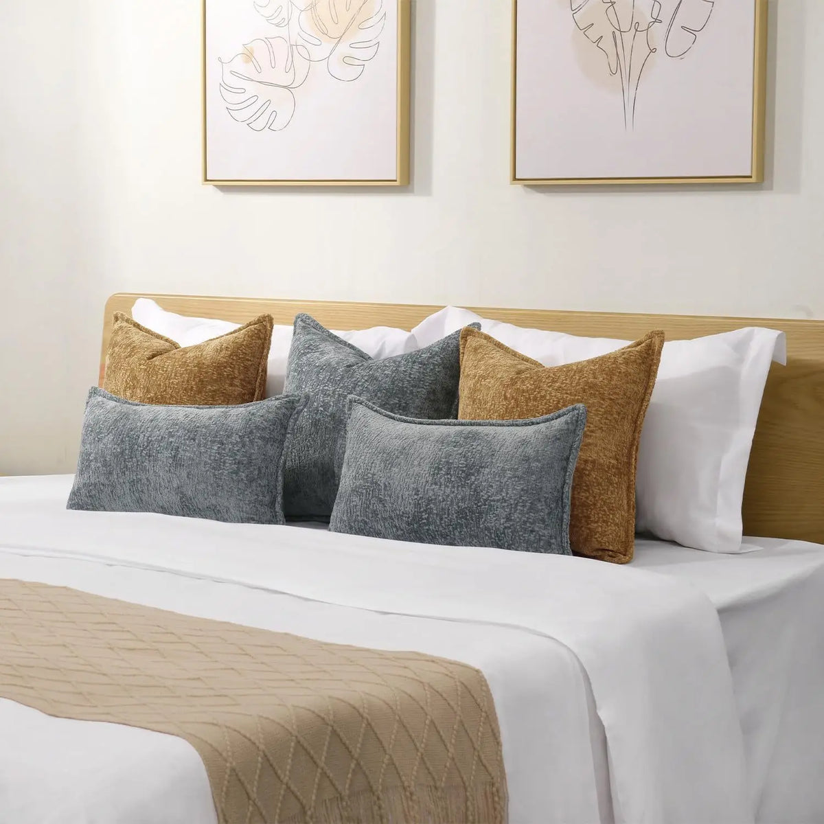 A collection of decorative cushion covers in shades of gray, beige, and white displayed on a bed.