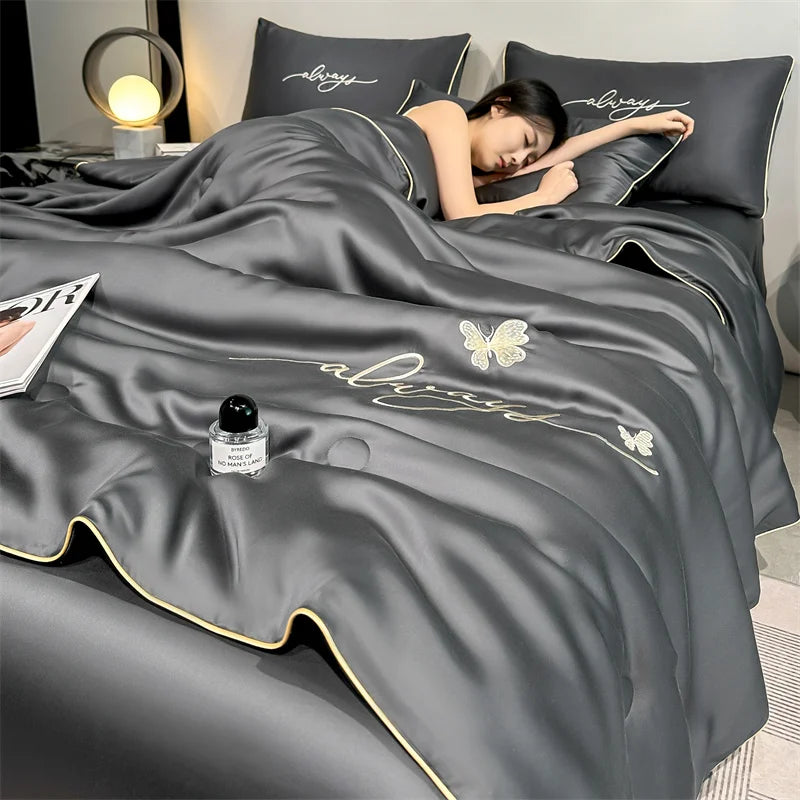 A dark gray ultra-soft comforter with embroidery featuring butterfly designs and pillows.