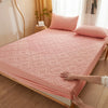A pink quilted mattress protector is shown being handled on a wooden bed frame.
