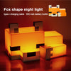 An orange fox-shaped night light made of light-emitting blocks resting on a wooden surface.