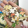 A hand holds a colorful jigsaw puzzle featuring a vibrant floral sugar skull design.