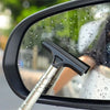 A black telescopic window cleaning squeegee with an adjustable silver handle is visible on a wet car window.
