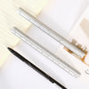 A close-up of an aluminium triangular scale ruler and a black pen resting on a sheet of paper.