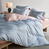 A luxury mulberry silk duvet cover set in soft blue and pink tones on a bed.