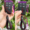 A black silicone key fob cover with a keyring attached, shown being held by a hand.