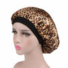 A woman wearing a gold and brown leopard print satin hair bonnet on a mannequin head.