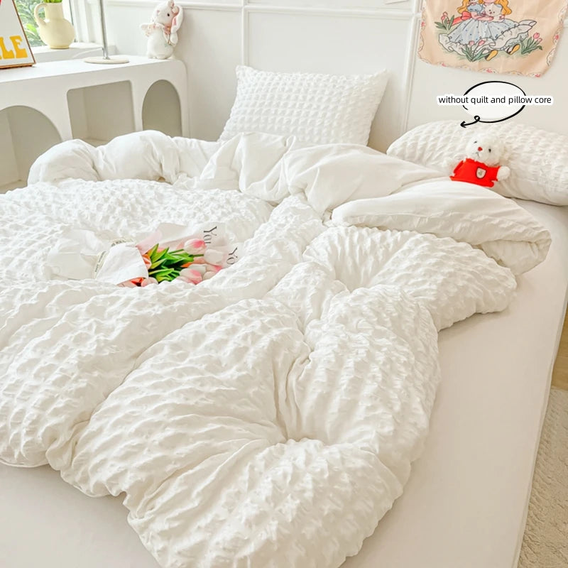 A white lightweight seersucker duvet cover set displayed on a bed with a decorative pillow and a small stuffed animal.