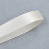 A roll of white double face satin ribbon, shown diagonally on a gray textured surface.