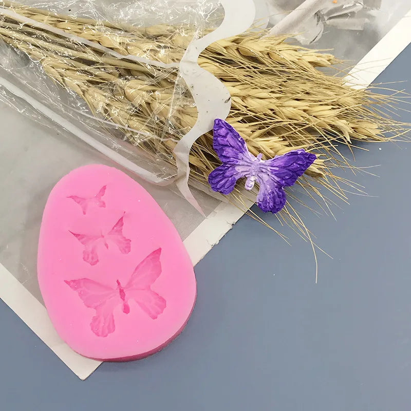 Pink silicone butterfly molds for soap, chocolate, and resin crafts displayed next to dried natural grasses.