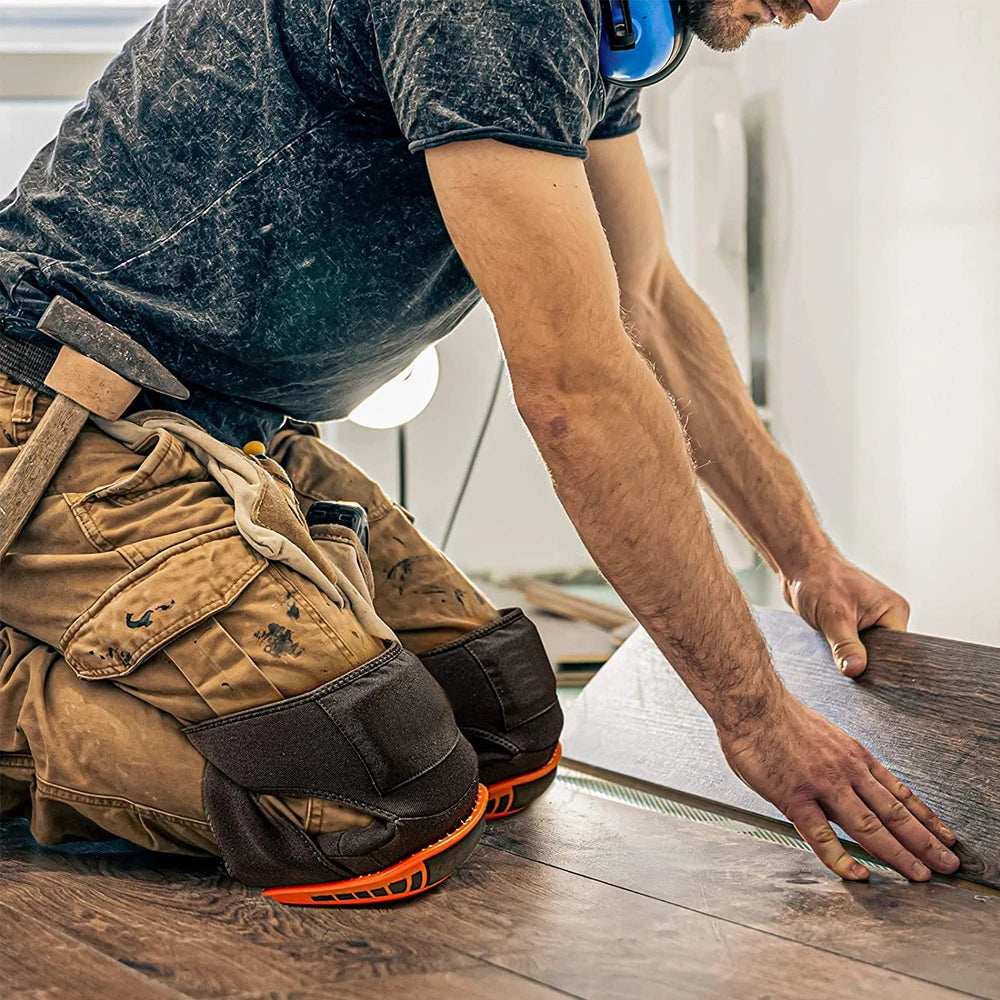A person wearing a dark shirt and work pants is using heavy-duty knee pads while working on a wooden surface.