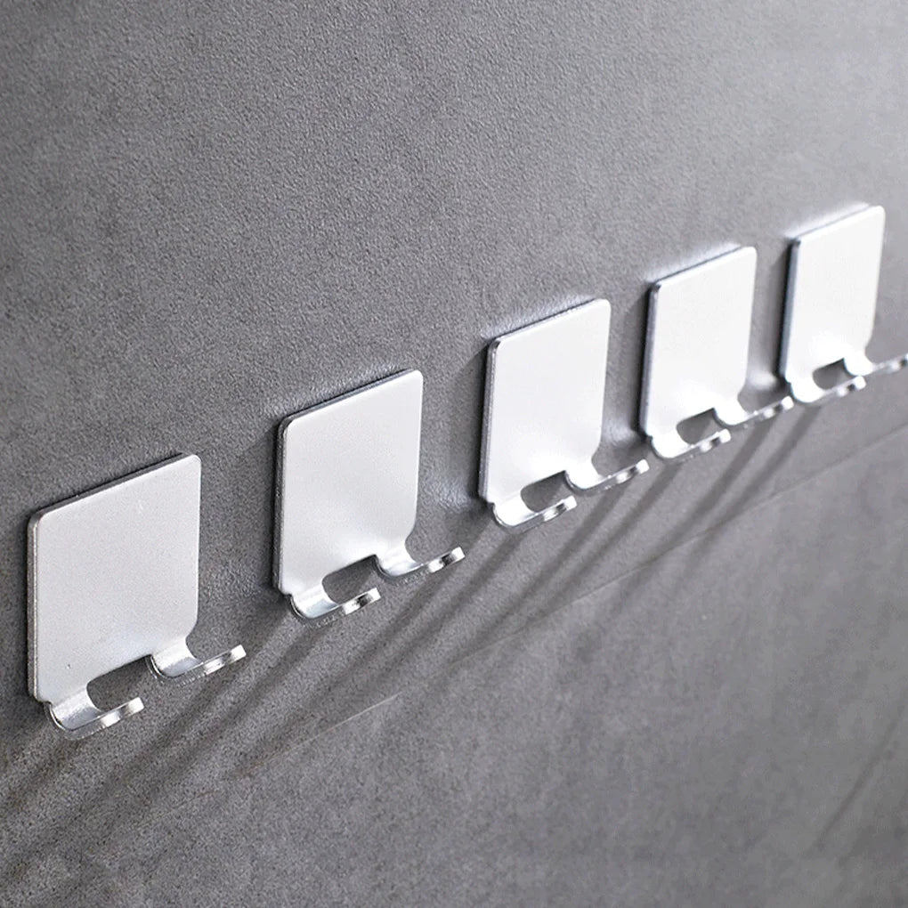 A row of white aluminum wall-mounted adhesive razor holders mounted on a gray wall.