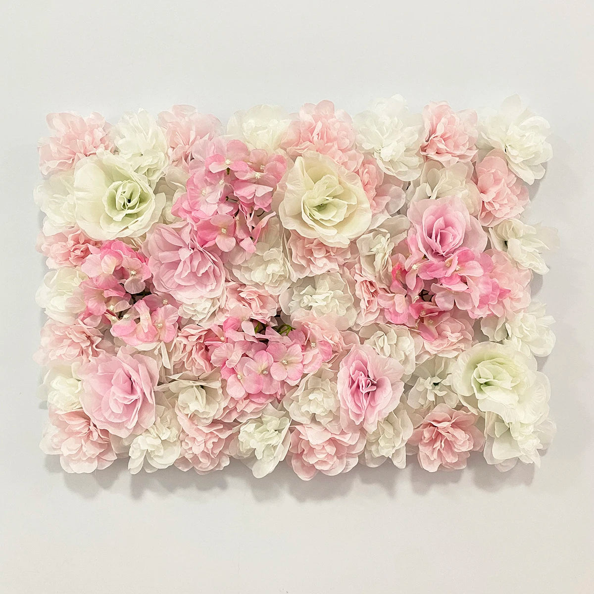 A dense wall panel of pink and white silk rose flowers for weddings and events.