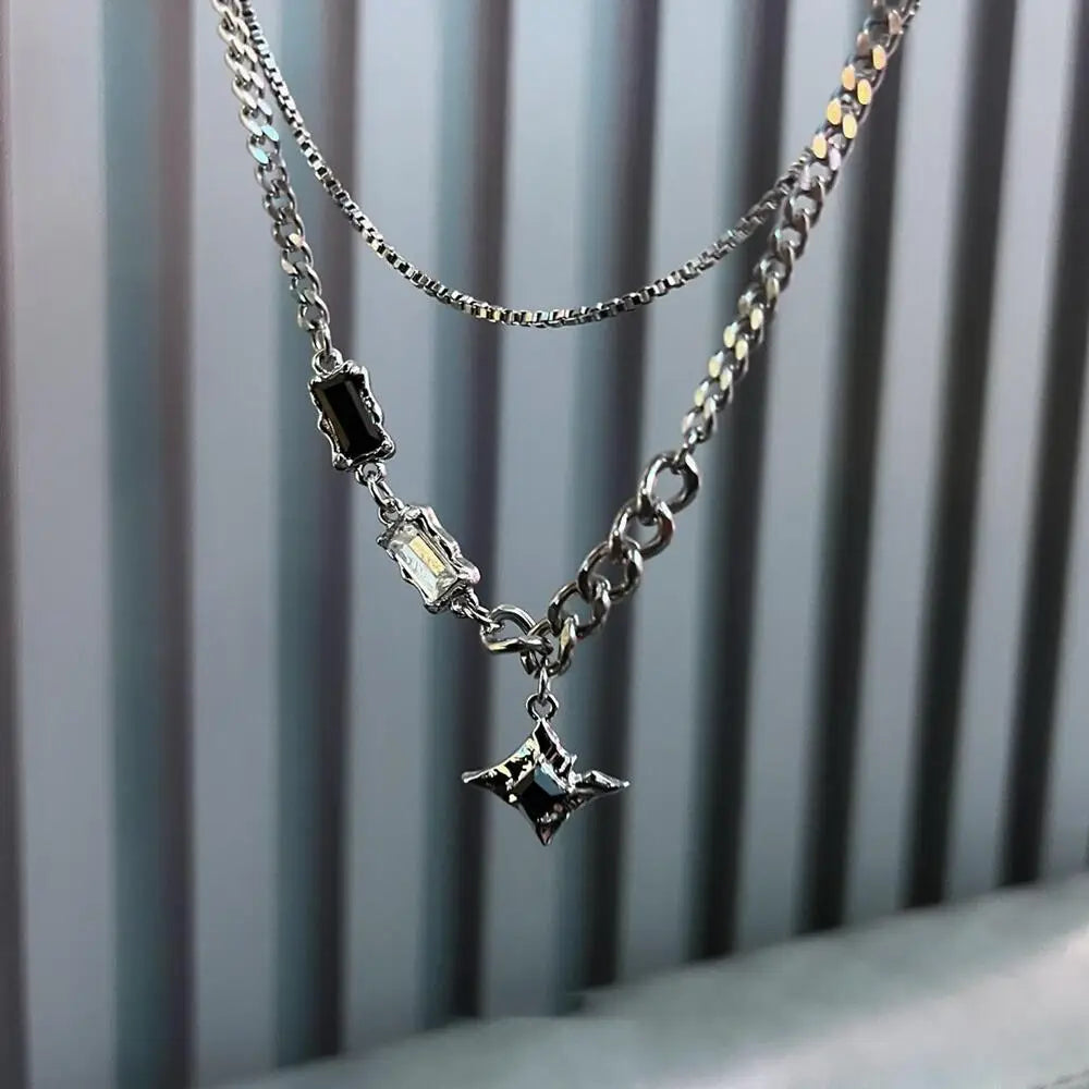 A silver double-layer necklace featuring dark gemstone and clear diamond star pendants.