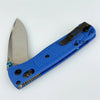 A blue folding pocket knife with a drop point blade and black handle is shown against a white background.