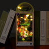 A DIY book nook kit featuring a miniature forest scene with glowing lights and foliage.