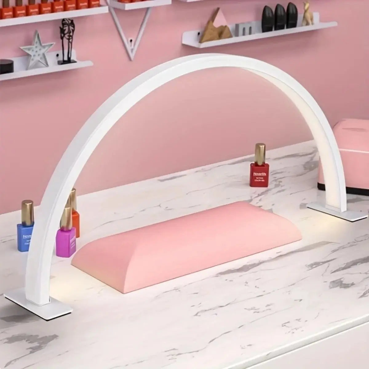 A white half-moon LED arc desk lamp illuminates a pink cosmetic tray on a marble surface.