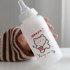 A hand holds a clear plastic water bottle with a pink drawing of a bear and text that says Happy Be happy every day