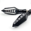 A black motorcycle turn signal indicator with a clear lens and chevron pattern.