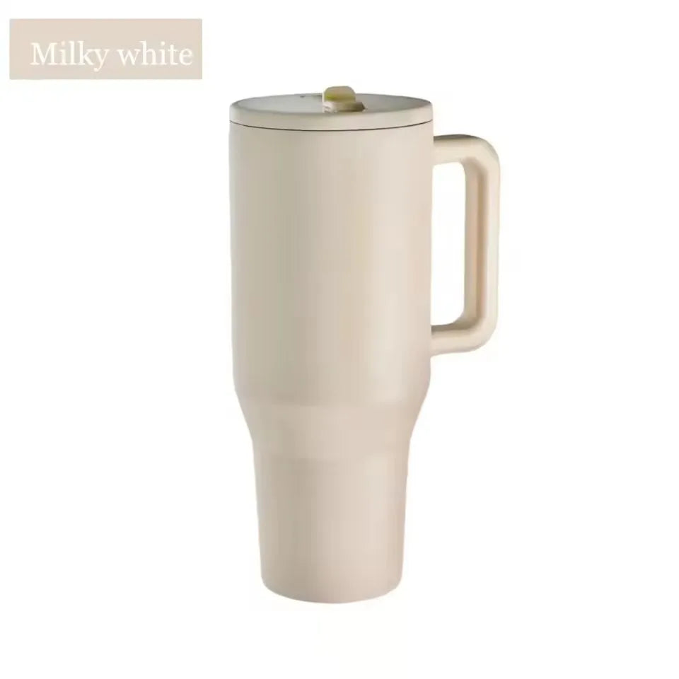 Un tumbler isotherme blanc crème avec une anse et une paille.