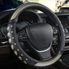 A close-up view of a black steering wheel with heart-shaped patterned leather covers inside a car interior.