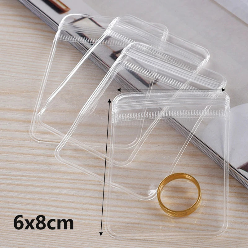 A transparent PVC jewelry pouch with a zip lock closure is shown on a wooden surface.