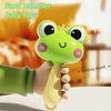 A hand is holding a green cartoon frog baby toy with a crown for a rustling sound sensory grasp toy