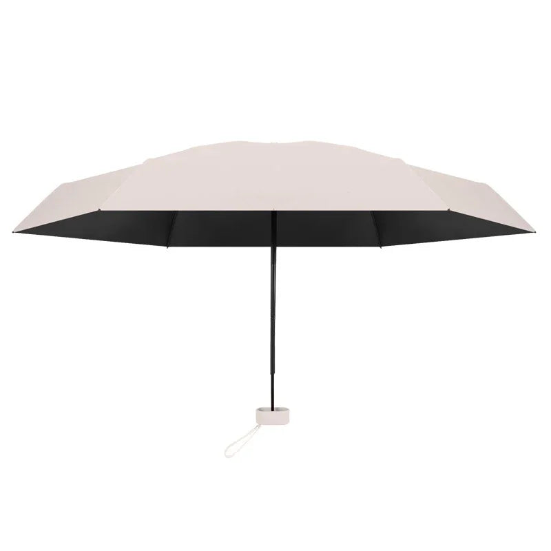 A beige compact travel umbrella with a black canopy and a visible handle.