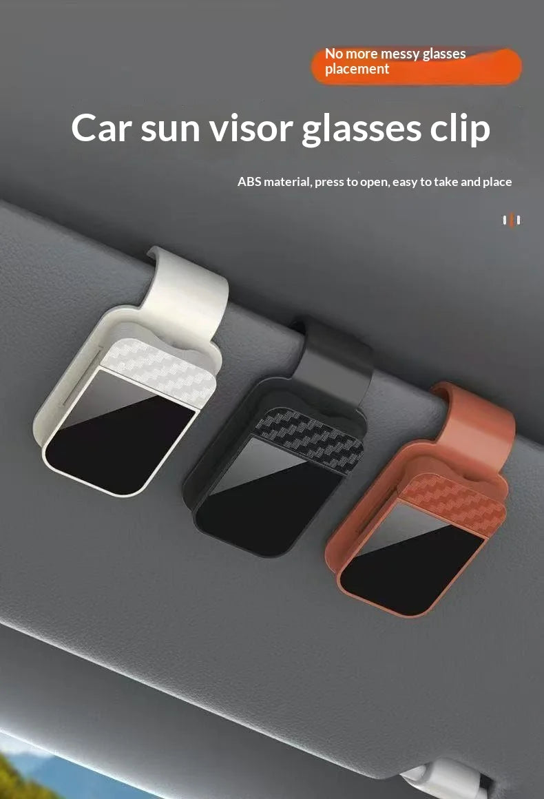 Three car sun visor glasses clips made of ABS material are shown in white, black, and pink on a gray car interior.