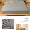 A gray fitted bed sheet set and pillowcase displayed on a wooden bed frame in a bright bedroom setting.