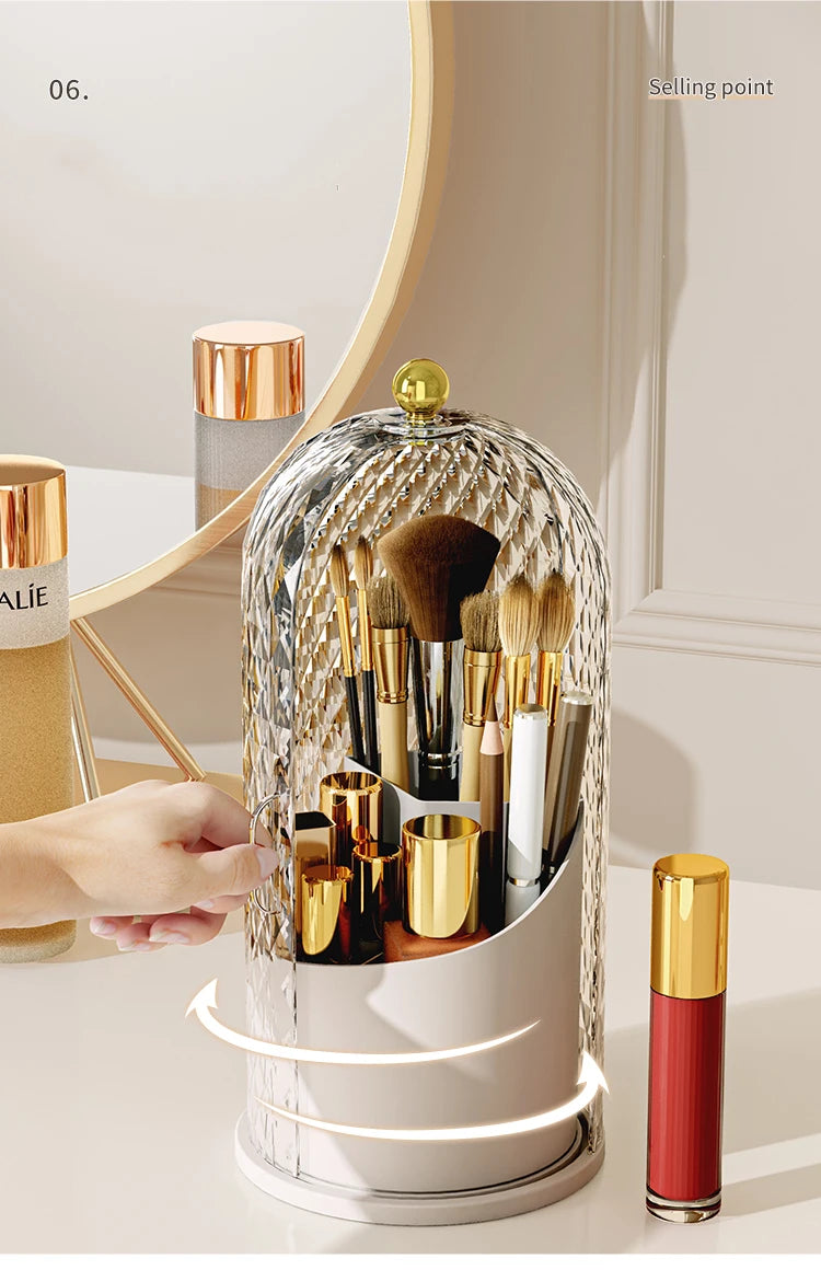 Organizador esférico giratorio y transparente para brochas de maquillaje con detalles dorados y tapa, sobre una superficie bl