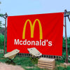 Grande bannière rouge avec le logo des arches dorées de McDonald's et le nom de la marque en texte blanc, installée à l'extér