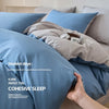 A close-up of a blue quilted duvet cover set and pillows on a bed, emphasizing cozy sleep.